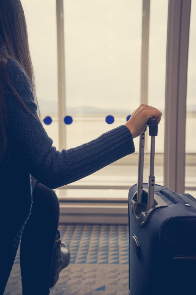Young woman in the airport, looking through the window at planes