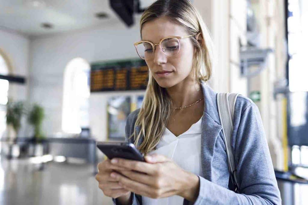 Woman with glasses on in the office looking down at her phone